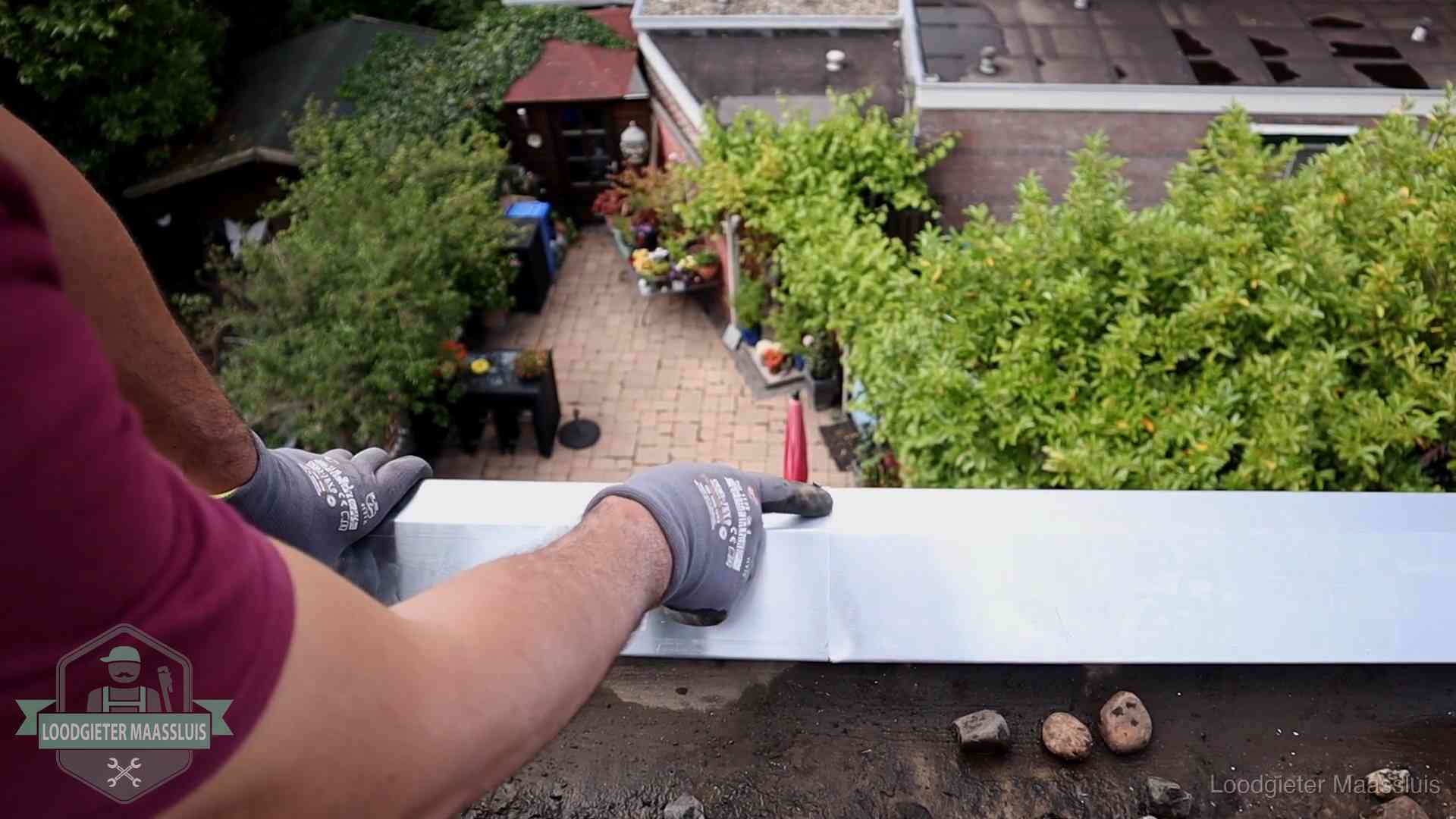 Daklekkage geregeld in Maassluis Vakman plaatst een daktrim op de dakrand van een woning in Maassluis