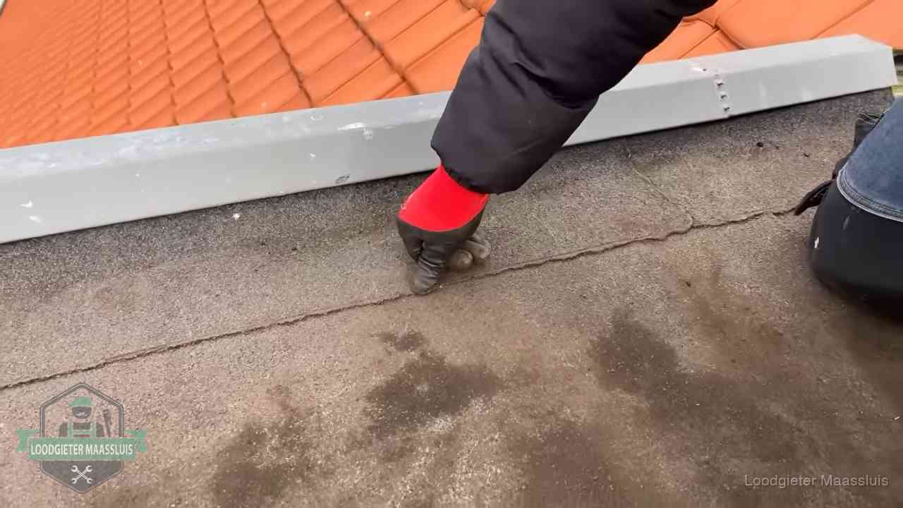 Lekkage bij de naad van een plat dak in Maassluis Vakman wijst een naad met vochtplekken aan op een bitumen plat dak in Maassluis