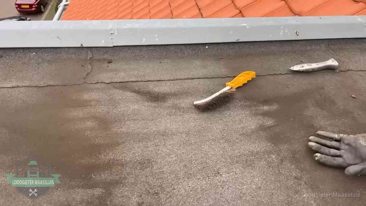 Kosten van daklekkage-reparatie in Maassluis Dakdekker bereidt een bitumen plat dak voor op reparatie bij de daktrim in Maassluis