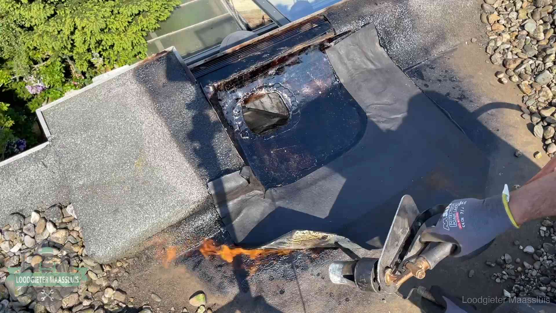 Daklekkage repareren in Maassluis Dakdekker brandt bitumen rond een doorvoer tijdens een daklekkage-reparatie in Maassluis