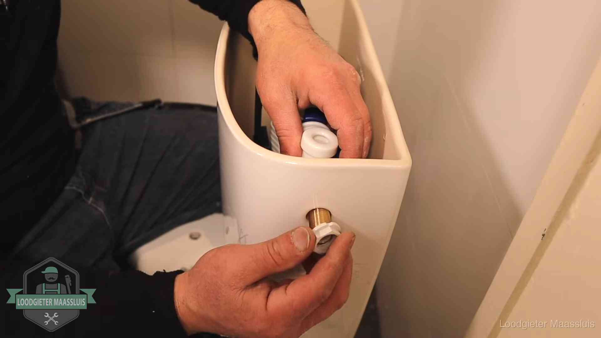Loodgieter monteert de vlotterkraan van een stortbak bij een toilet in Maassluis