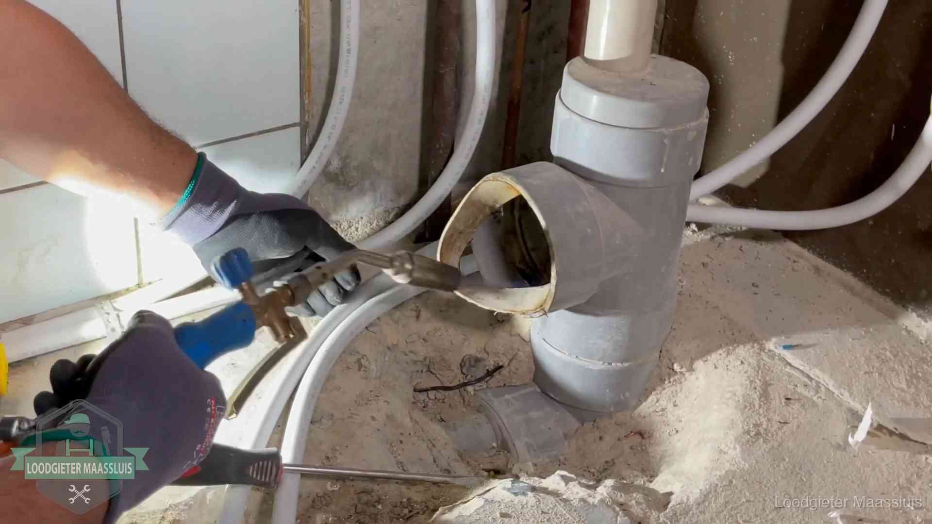 Loodgieter werkt met brander en messing kraanwerk aan leidingen in Maassluis