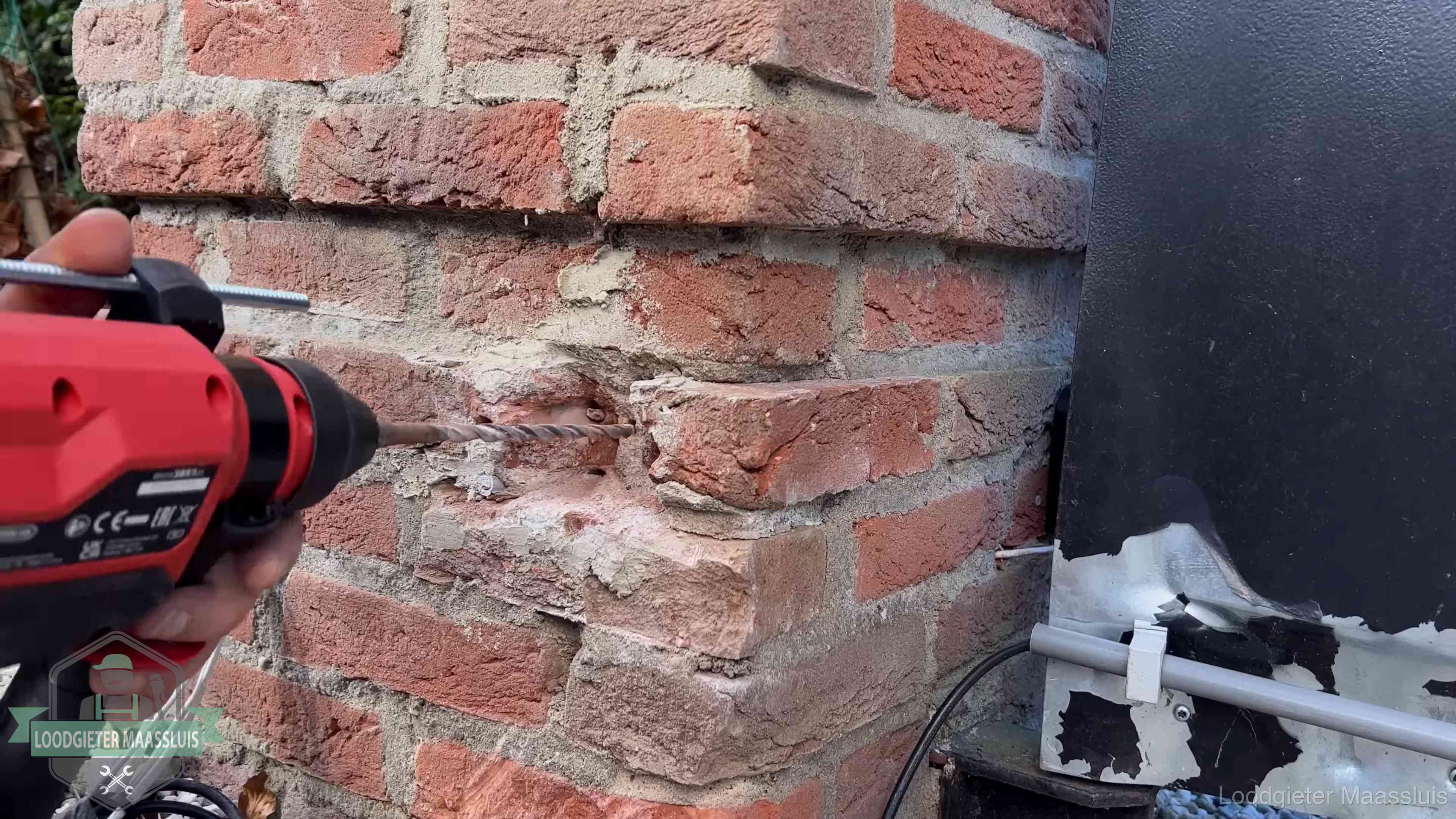 Vakman boort in de buitenmuur van een woning in de regio Maassluis
