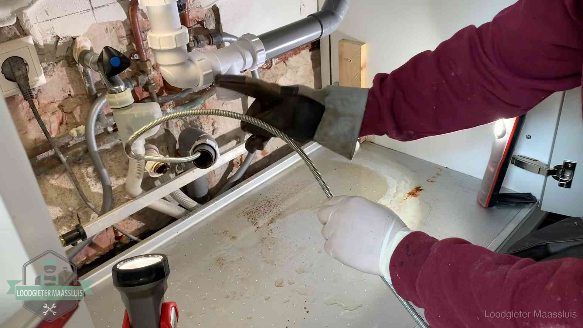 Spiraal of hogedruk in Maassluis Ontstoppingsveer gaat in een geopende sifonaansluiting onder het aanrecht in Maassluis