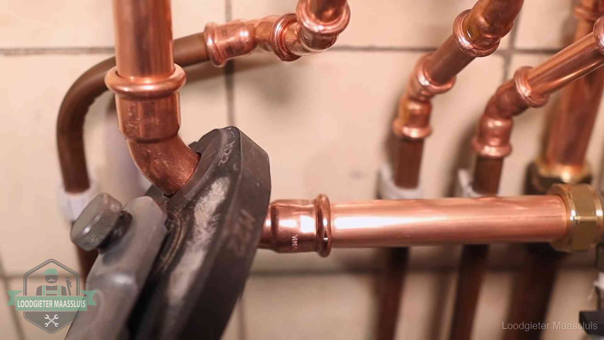 Persmachine perst een koperen fitting op nieuw leidingwerk in Maassluis