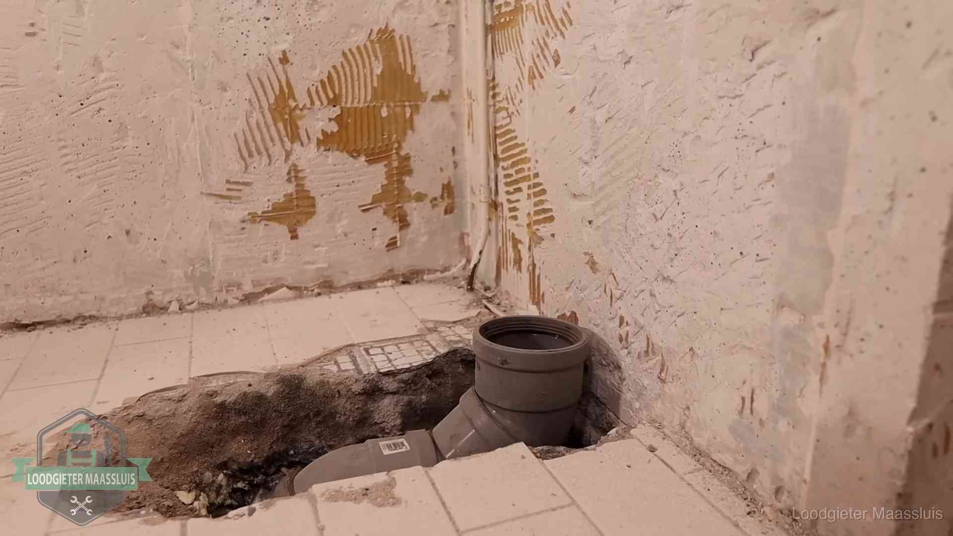 Verzakt riool herstellen in Maassluis Opengebroken vloer met een nieuwe pvc-rioolbocht in een gegraven sleuf in Maassluis