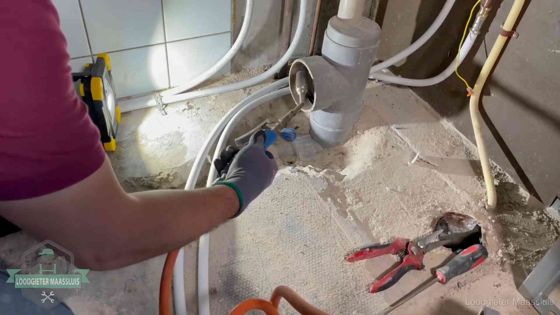 Loodgieter werkt aan leidingen bij een pvc-standleiding in een appartement in Maassluis