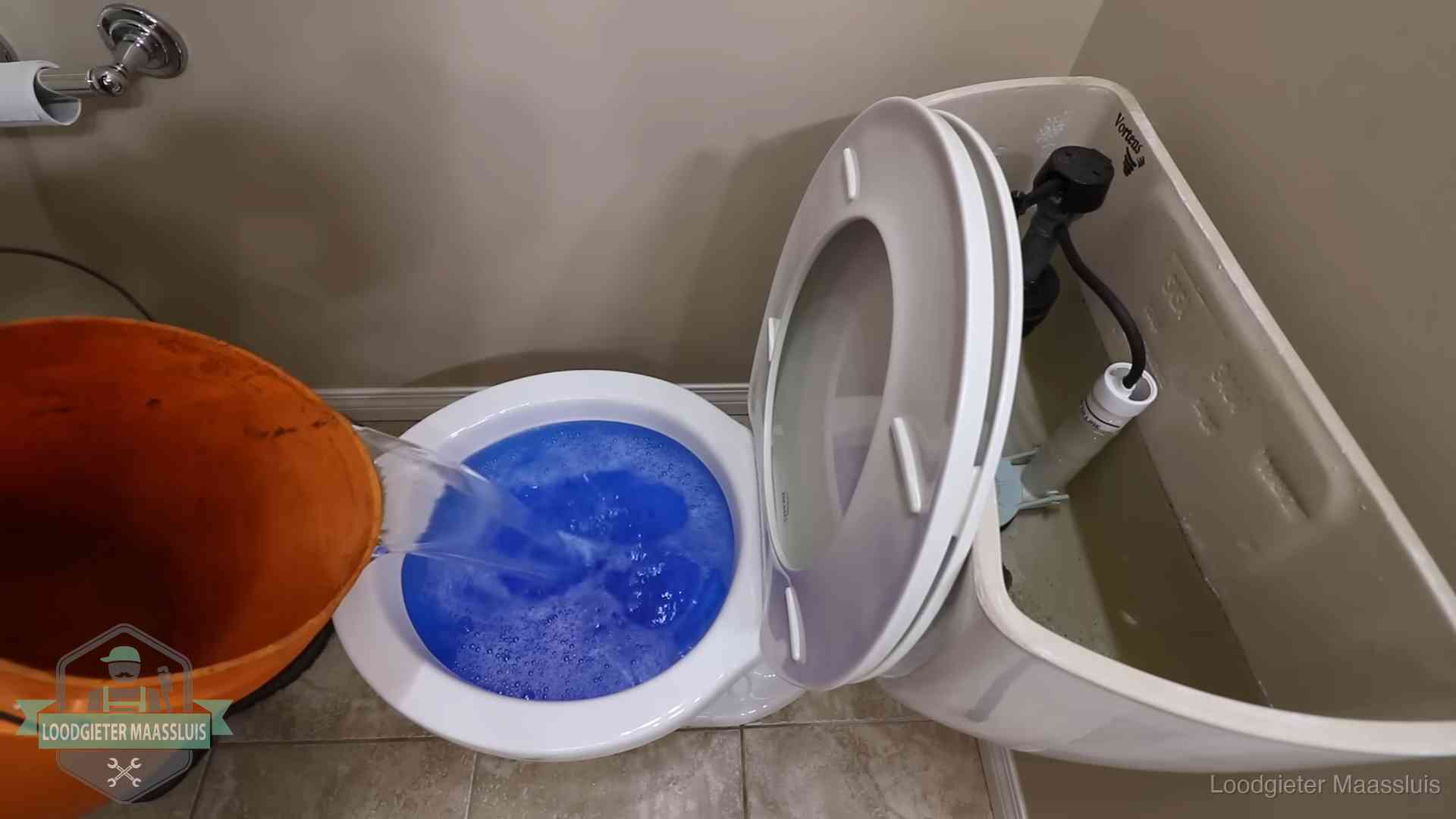 Water bij de wc-pot wordt met een emmer weggewerkt om schade te beperken in Maassluis